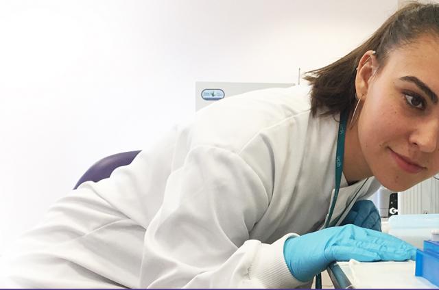 A researcher looking at a test tube